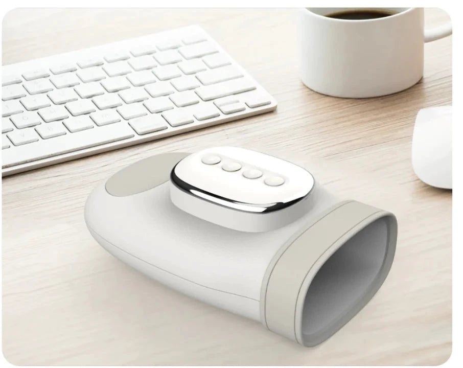 White wireless hand and wrist massager with a rounded cuff and four-button control panel, on a desk beside a keyboard.